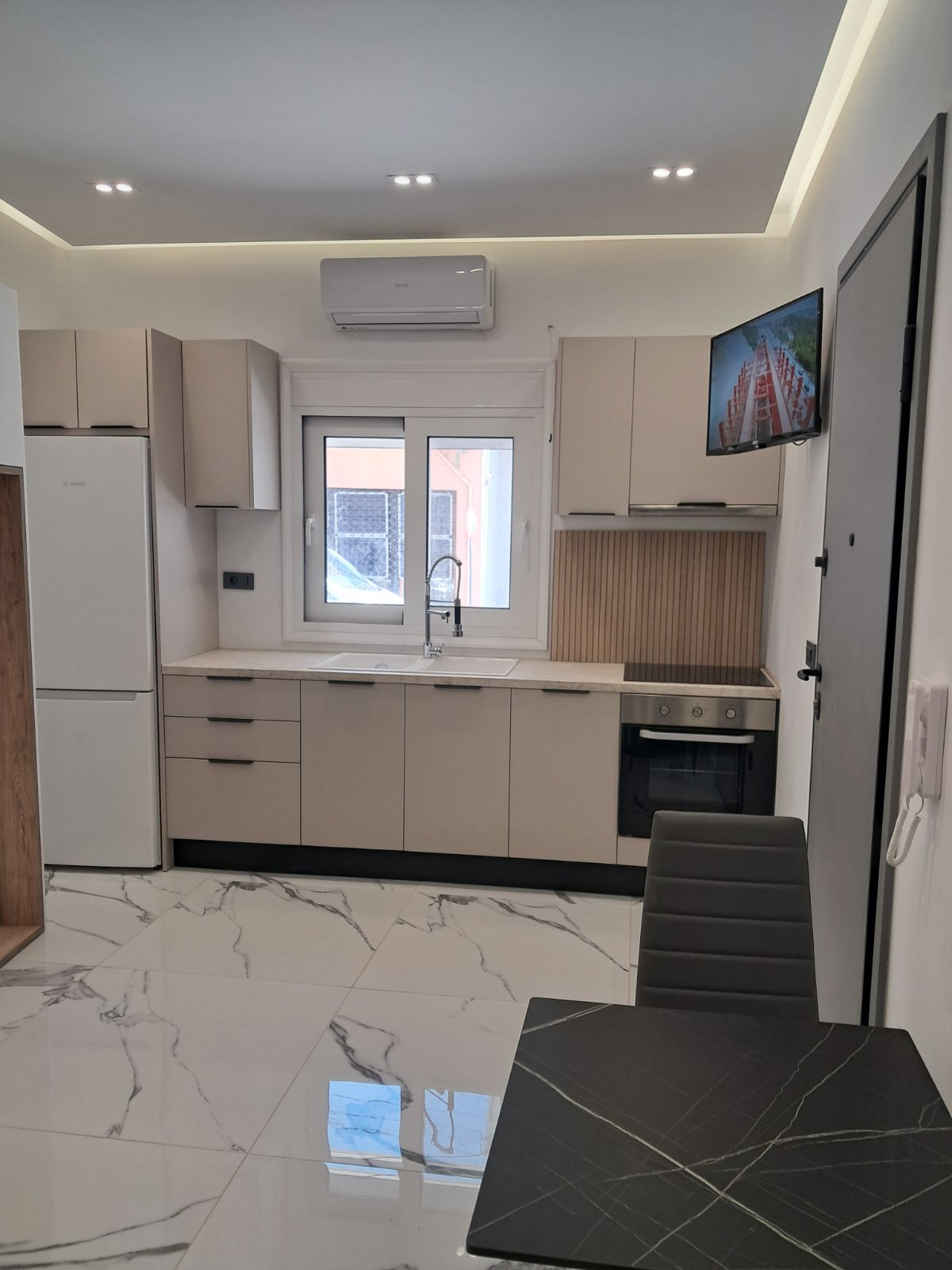 Φωτεινή compact κουζίνα με custom ντουλάπια και ξύλινη επένδυση
